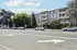 Modern apartment building with spacious balconies, lush greenery, and convenient street parking.
