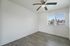 Bright, airy room with sleek wooden flooring and large window offering scenic views, complemented by a modern ceiling fan.