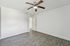 Bright and modern empty room with sleek wood flooring, ceiling fan, and spacious sliding closet doors.