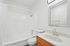 Bright, modern bathroom featuring a sleek bathtub, elegant vanity with mirror, and stylish fixtures.
