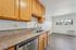 Bright, modern kitchen with granite countertops, stainless steel dishwasher, and warm wood cabinetry opening to a sunlit dining area.