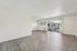 Bright, spacious living area with elegant wood flooring and large windows opening to a balcony with a charming view.