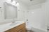 Bright and elegant bathroom boasting a sleek vanity, stylish mirror, and modern fixtures, offering a serene space for relaxation.