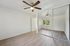Modern bedroom with sleek wooden flooring, mirrored closet doors, and a ceiling fan, offering a spacious and airy feel.