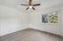 Bright and airy room with modern flooring, large window, and ceiling fan, offering serene views and natural light.