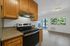 Bright and modern kitchen with sleek appliances, elegant wooden cabinets, and a spacious open-plan living area connecting to a balcony with scenic views.