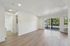Bright and spacious living area featuring sleek wooden floors, large sliding glass doors with balcony view, and abundant natural light.