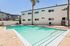Inviting apartment pool area with crystal-clear water, surrounded by a relaxing patio and lounge chairs, perfect for sunny days.