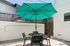 Chic outdoor patio featuring a stylish table set with a vibrant turquoise umbrella, perfect for entertaining in a sunlit, private space.