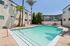 Inviting outdoor pool area with palm trees, surrounded by modern apartments and lounge seating for relaxation.