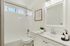 Elegant bathroom with modern fixtures, featuring a sleek vanity, stylish mirror, and inviting bathtub.
