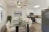 Elegant dining area with a glass table and plush chairs, adjacent to a modern kitchen featuring stainless steel appliances and white cabinetry.