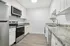 Modern kitchen with sleek stainless steel appliances, granite countertops, white cabinetry, and stylish wood flooring.