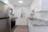 Bright, modern kitchen with granite countertops, white cabinets, stainless steel appliances, and wood flooring.