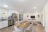 Elegant open-plan living space with a modern kitchen, stylish dining area, and cozy living room. Features polished wooden floors, stainless steel appliances, and outdoor access.