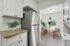 Modern kitchen view featuring a stainless steel refrigerator, white cabinetry, and an adjoining dining area with natural light and contemporary decor.