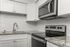 Modern kitchen with sleek stainless steel appliances, granite countertops, and elegant white cabinetry accentuated by a glossy subway tile backsplash.