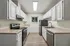 Modern kitchen with sleek stainless steel appliances, elegant white cabinetry, and natural light from a large window.