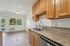 Bright kitchen area with modern wooden cabinetry, sleek granite countertops, and a large window offering scenic views and natural light.