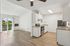 Bright and airy open-concept kitchen and living space with modern appliances and sliding glass door leading to a scenic balcony.