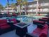 Inviting outdoor pool area with red cushioned seating, surrounded by a white apartment complex with balconies.