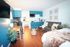 Bright studio apartment featuring a modern kitchenette, cozy seating area, and warm wooden flooring.