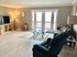 Inviting living room with natural light, modern furnishings, and a glass coffee table.