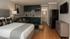 Modern studio apartment with elegant hardwood floors, featuring a cozy bed, sleek kitchenette, and a stylish seating area. Perfect blend of comfort and functionality.
