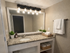 Elegant modern bathroom with granite countertop, stylish lighting, and fresh towels on wooden shelves.