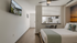 Modern apartment bedroom with cozy bedding, sleek ceiling fan, and a chic kitchenette, perfect for comfort and style.