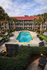 Luxurious apartment complex with a sparkling pool, surrounded by lush greenery and elegant seating, offering a resort-style vibe.