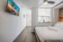 Bright and inviting bedroom featuring a modern ceiling fan, wall-mounted TV, and a serene decorative view, all enhancing a relaxing ambiance.