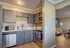 Modern kitchen with sleek grey cabinets and stainless steel appliances opening into a cozy living room with warm lighting and contemporary decor.