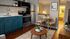 Charming apartment interior featuring an open kitchen with vibrant cabinetry, cozy dining area, and modern living space with warm wooden flooring.