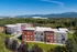 Charming apartment complex surrounded by lush greenery and stunning mountain views, featuring modern architecture and inviting outdoor spaces.