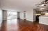 Bright, open-plan living area with rich wooden floors, modern kitchen and large window with outdoor view.