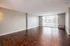 Spacious, sunlit living room featuring elegant wood flooring and large sliding glass doors.
