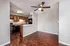 Charming apartment interior featuring a modern kitchen with sleek cabinets, granite countertops, and a cozy dining area with elegant wood flooring and a ceiling fan.