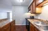 Charming kitchen space with polished granite countertops, warm wooden cabinetry, and modern appliances, leading to a bright living area.