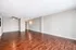 Spacious apartment with rich wooden flooring, contemporary ceiling fan, and elegant lighting, offering a warm and inviting atmosphere.