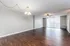 Spacious open-plan living room with elegant wooden flooring, modern ceiling fan, and large windows offering abundant natural light.