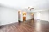 Spacious open-concept living area with elegant wooden flooring, ceiling fan, and bright natural lighting, adjacent to a modern kitchen.