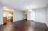 Spacious open-plan living area with elegant dark wood flooring, bright kitchen, and modern lighting.