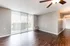 Bright and airy living room with elegant hardwood floors, modern ceiling fan, and large sliding doors leading to a private balcony.