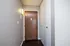 Inviting apartment entryway featuring a warm wooden door and sleek white storage closets, perfect for a stylish, welcoming space.