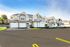 Charming modern townhouses with beige siding and stone accents, featuring tidy landscapes and spacious driveways under a clear blue sky.