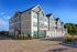 Charming three-story apartment complex showcasing modern architecture and inviting landscaping under a clear blue sky.