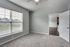 Bright and airy bedroom with plush carpet, large window with blinds, and modern ceiling fan, offering a tranquil view of greenery outside.