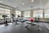 Modern fitness center with state-of-the-art cardio equipment, weight benches, and a vibrant red exercise ball, flooded with natural light through large windows.