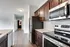 Sleek kitchen with stainless steel appliances and dark wood cabinets leading to a bright hallway.